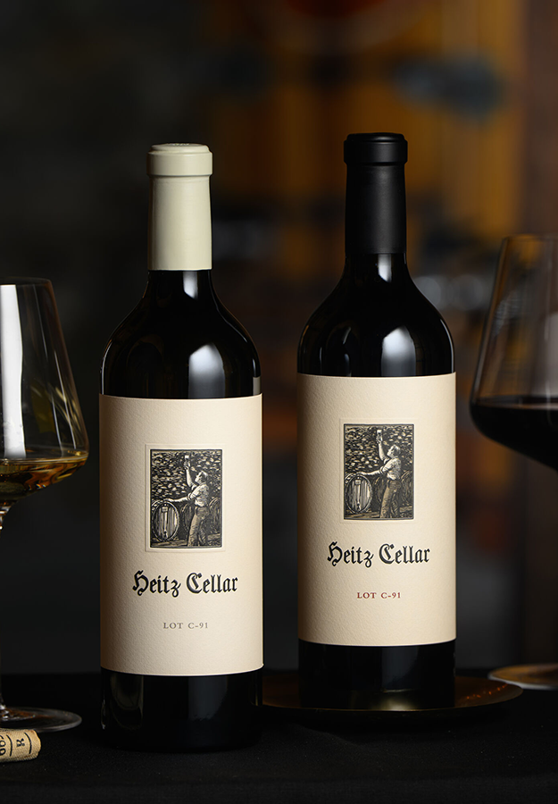 Heitz Cellar Holiday 2023 - Lot C-91 Duo: A bottle of 2021 Lot C-91 Sauvignon Blanc and 2019 Lot C-91 Cabernet Sauvignon on a table with two glasses of wine.