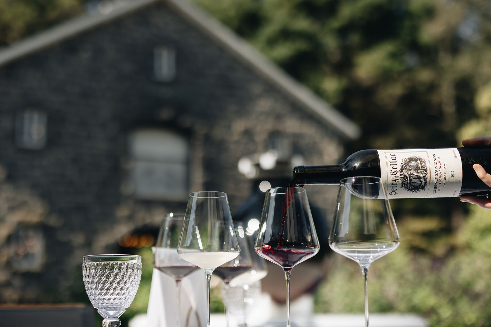 A bottle of Heitz Cellar Cabernet Sauvignon being poured into a glass outside at The Estate at Heitz Cellar.