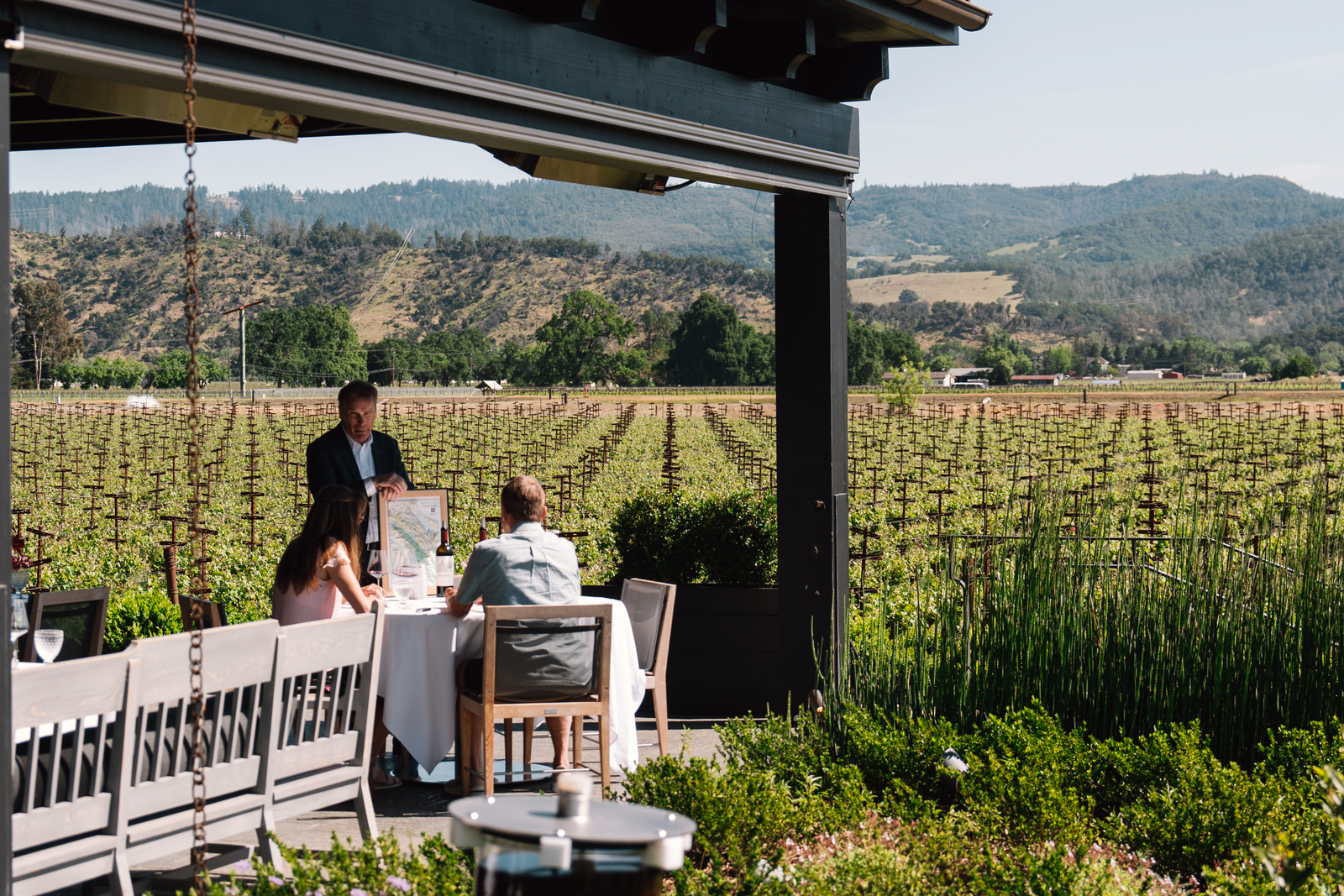 A couple enjoying a tasting at The Salon at Heitz Cellar outside overlooking the vineyard.