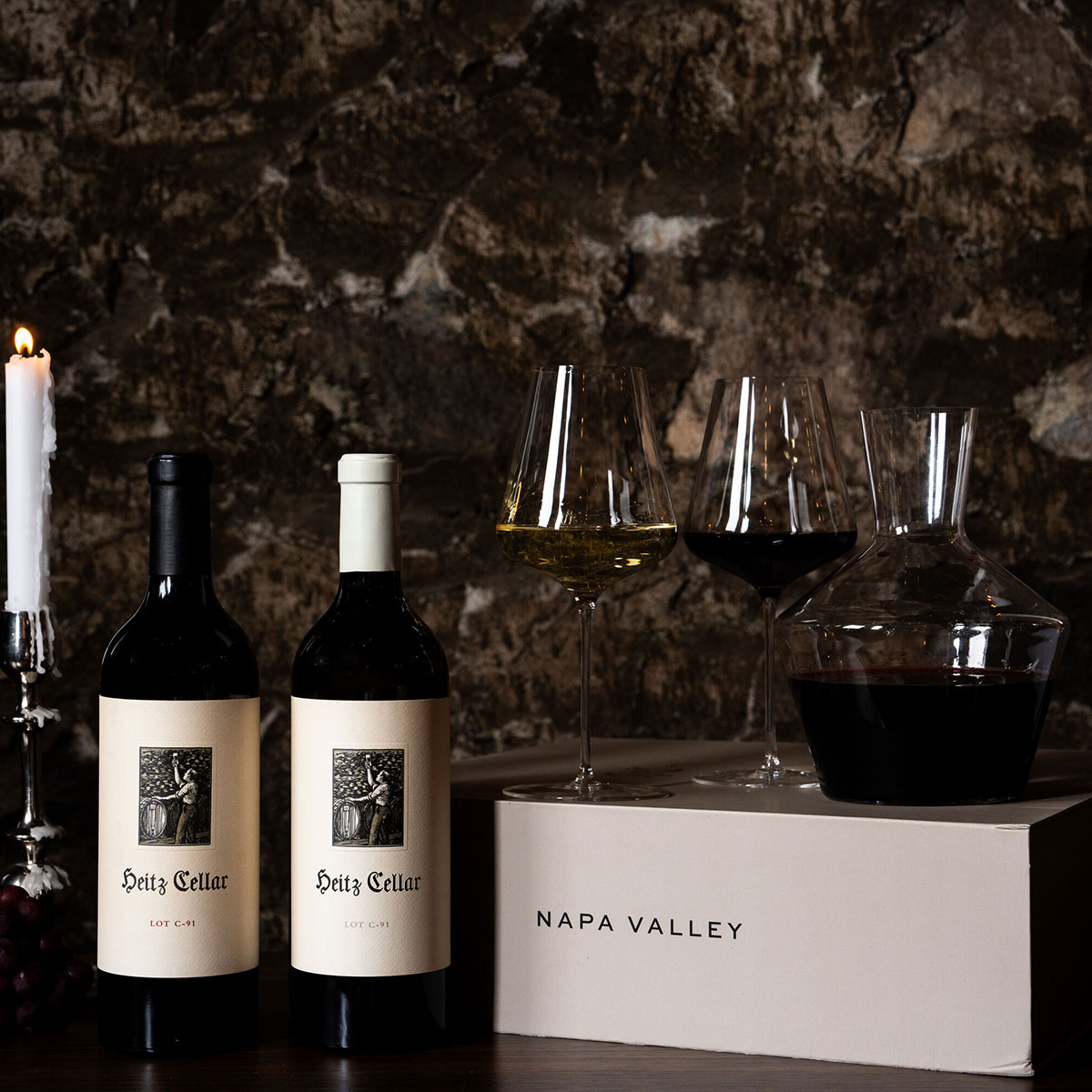 Heitz Cellar Holiday 2024 - Lot C-91 Duo: A bottle of 2022 Lot C-91 Sauvignon Blanc and 2019 Lot C-91 Cabernet Sauvignon on a table with two glasses of wine.