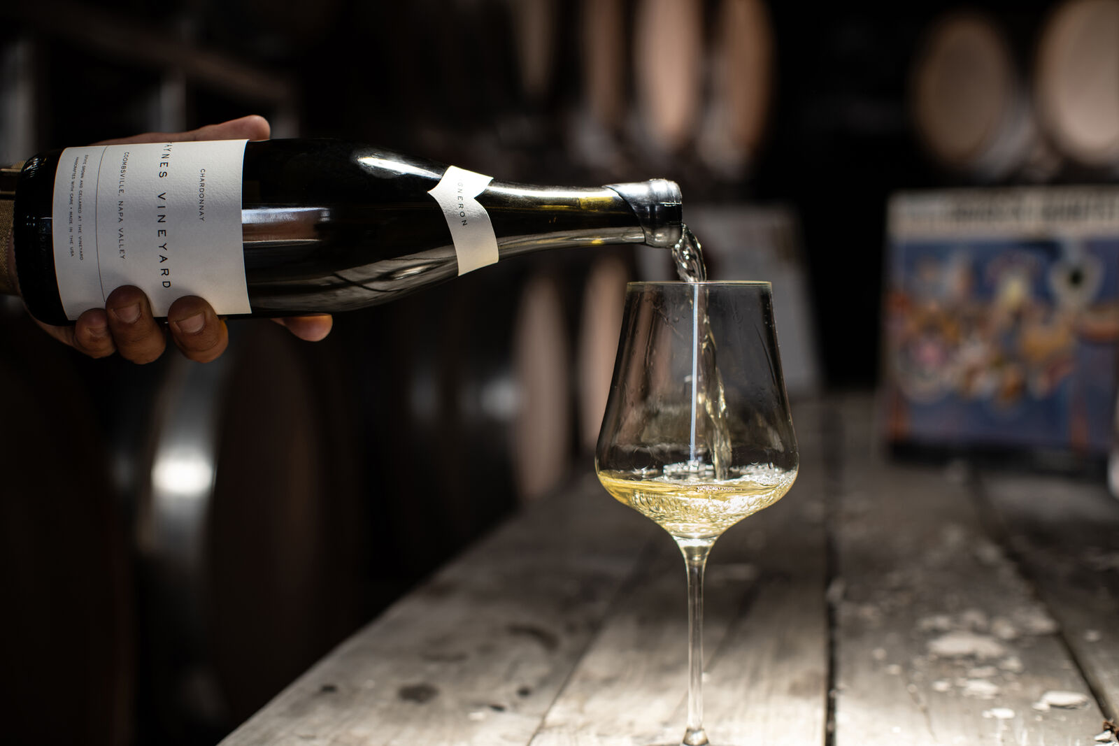 A bottle of Haynes Vineyard Vigneron Chardonnay being poured into a glass inside the cellar.